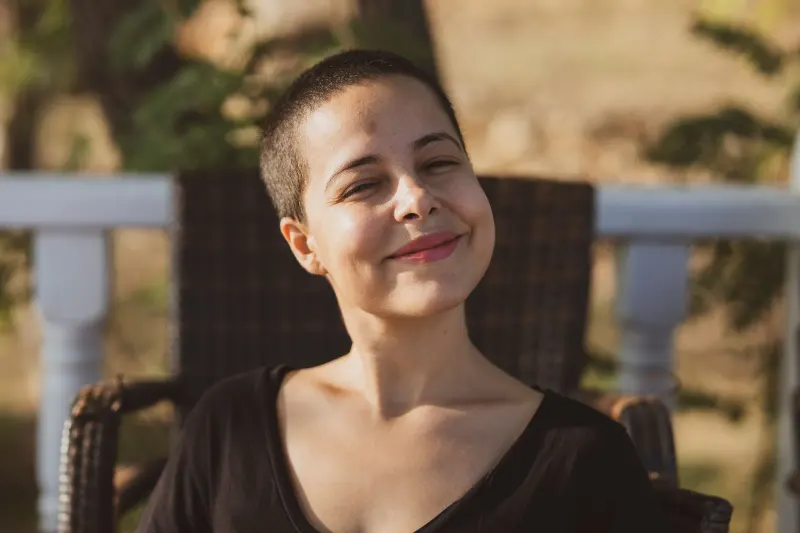 Portrait of a smiling woman enjoying a sunny day outdoors.