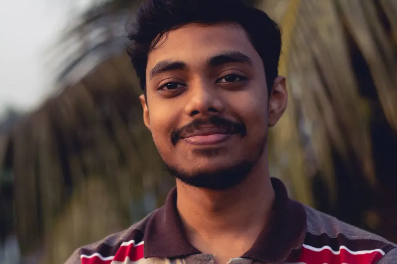 Candid close-up portrait of a smiling man with a natural background, exuding warmth and friendliness.