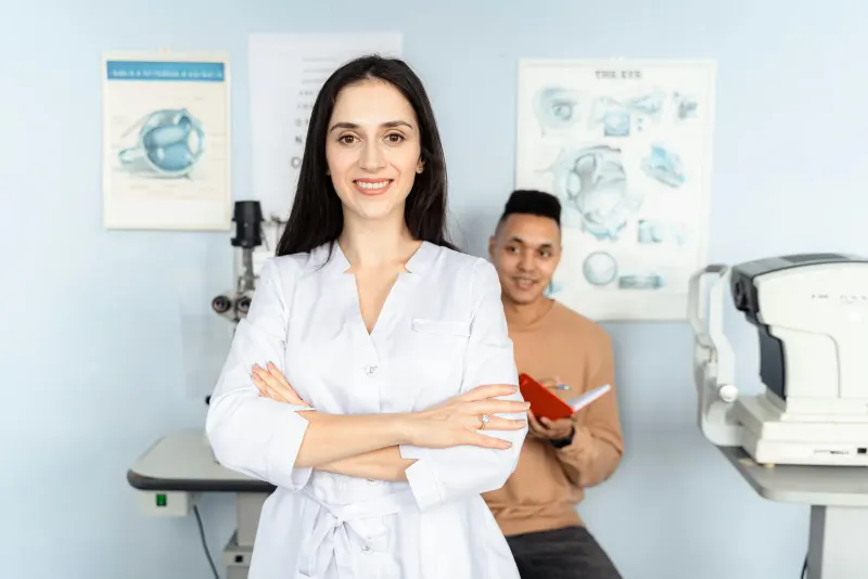 Portrait of a confident female doctor smiling with arms crossed in a medical office setting.