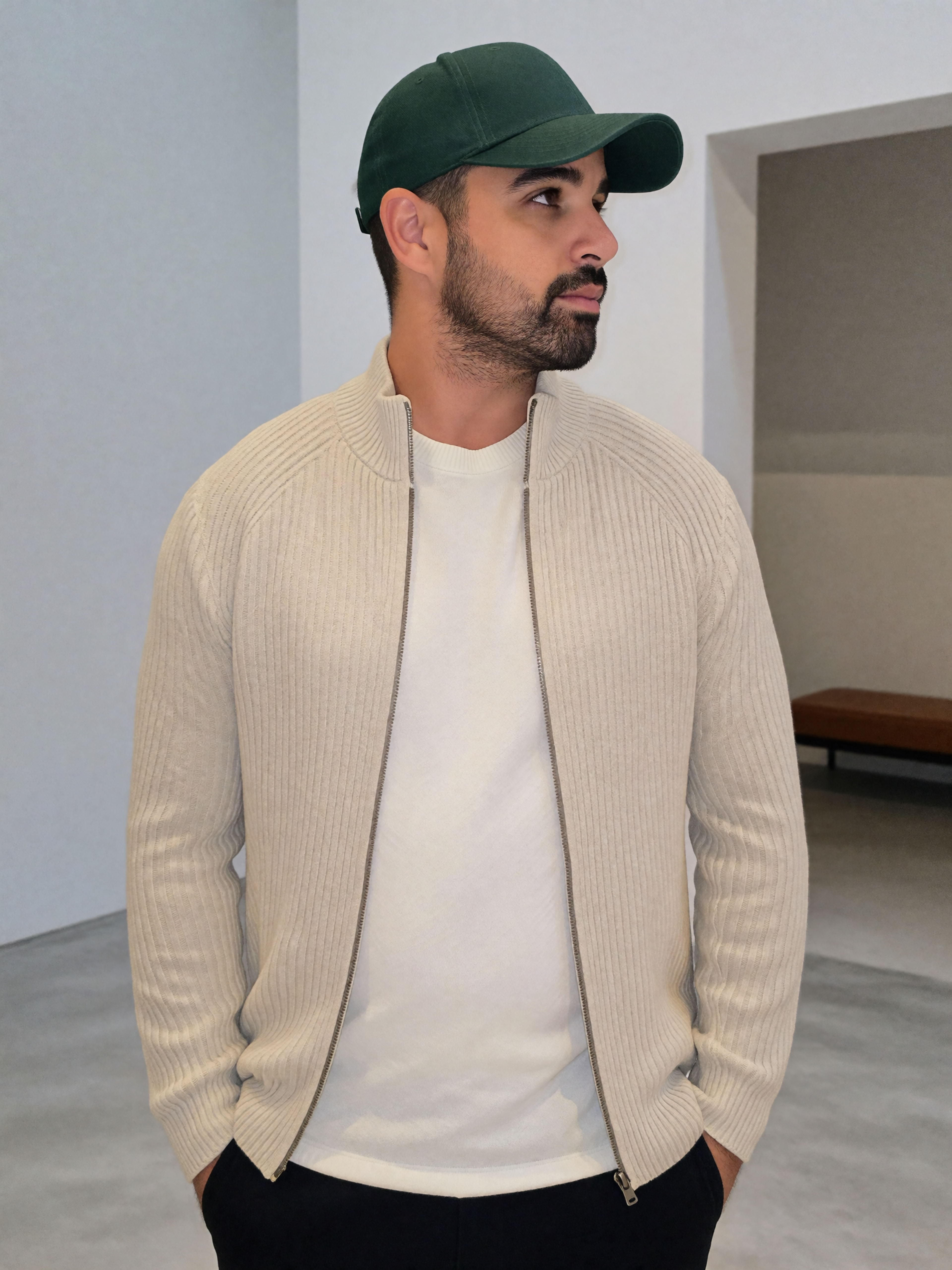 Digitaler Zwilling von Mousaab Ainouche in beiger Strickjacke, weißem T-Shirt und grüner Cap bei einem modernen Casual-Fashion-Shooting.