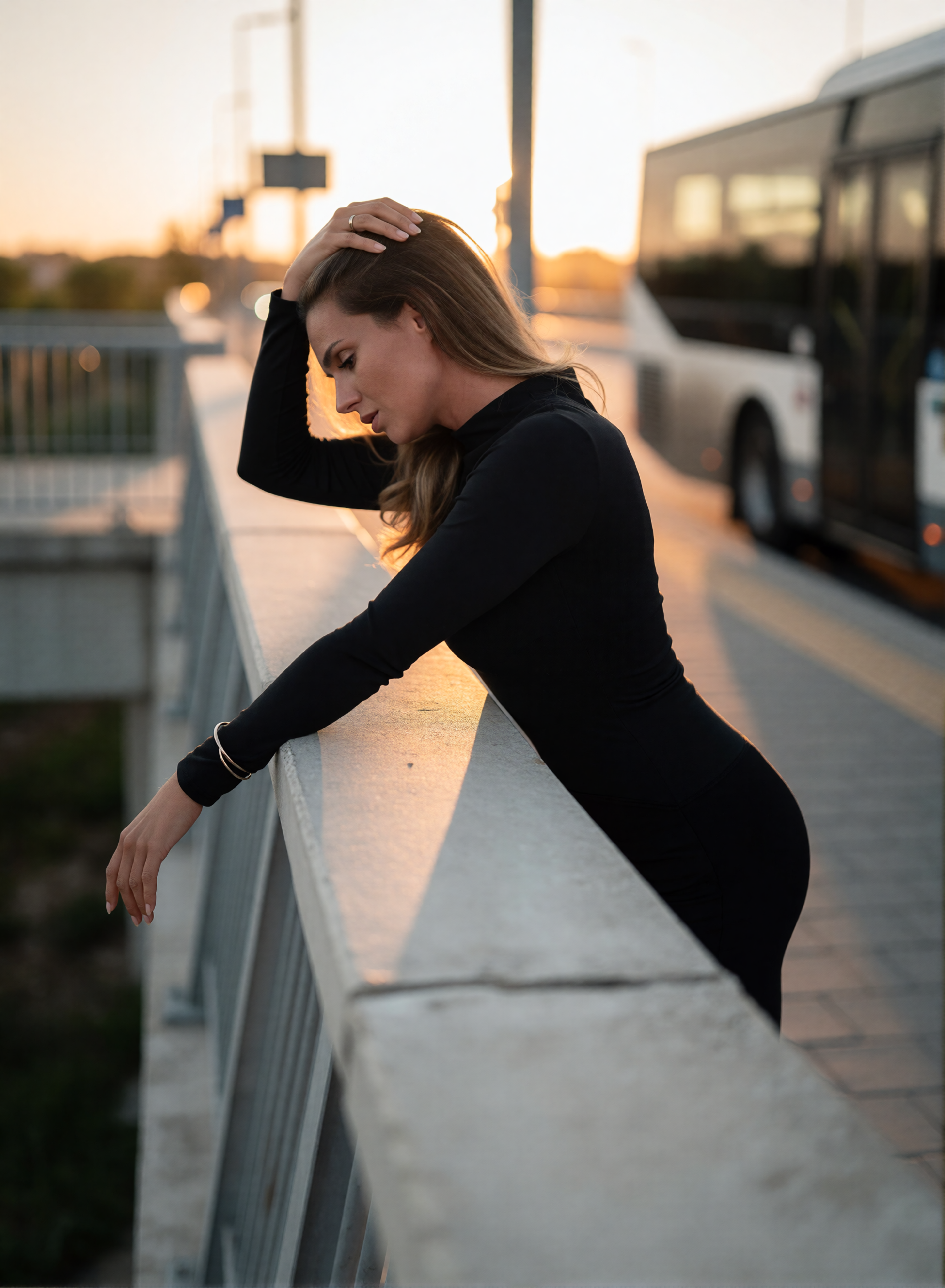 Digital twin of Nicole Funken in a black dress at a fashion shoot at a bus stop at sunset.