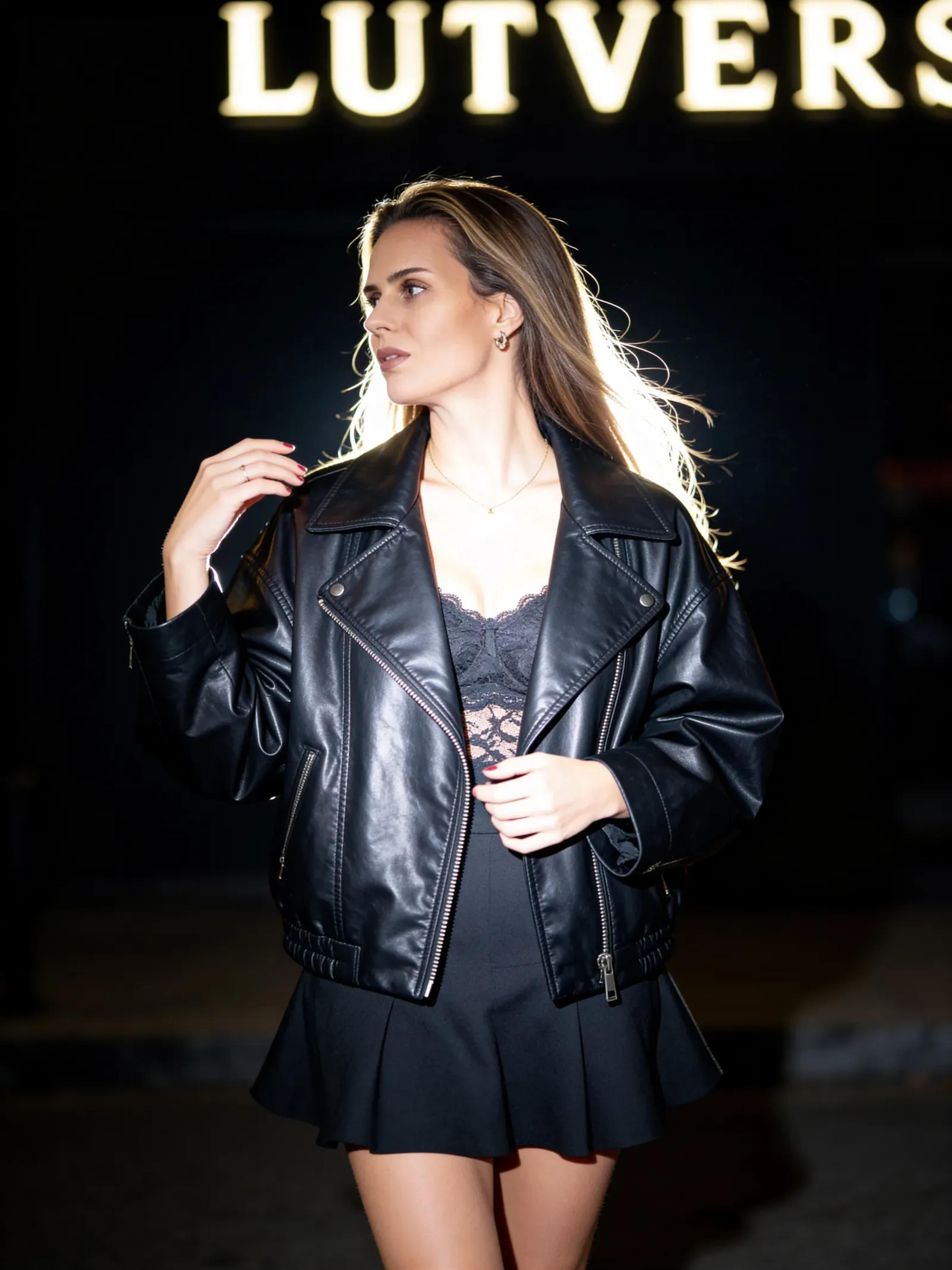 Fotorealistischer weiblicher Digitaler Zwilling in Lederjacke bei Event mit Schriftzug im Hintergrund, Lifestyle Porträt, Trickhouse KI-Model-Agentur
