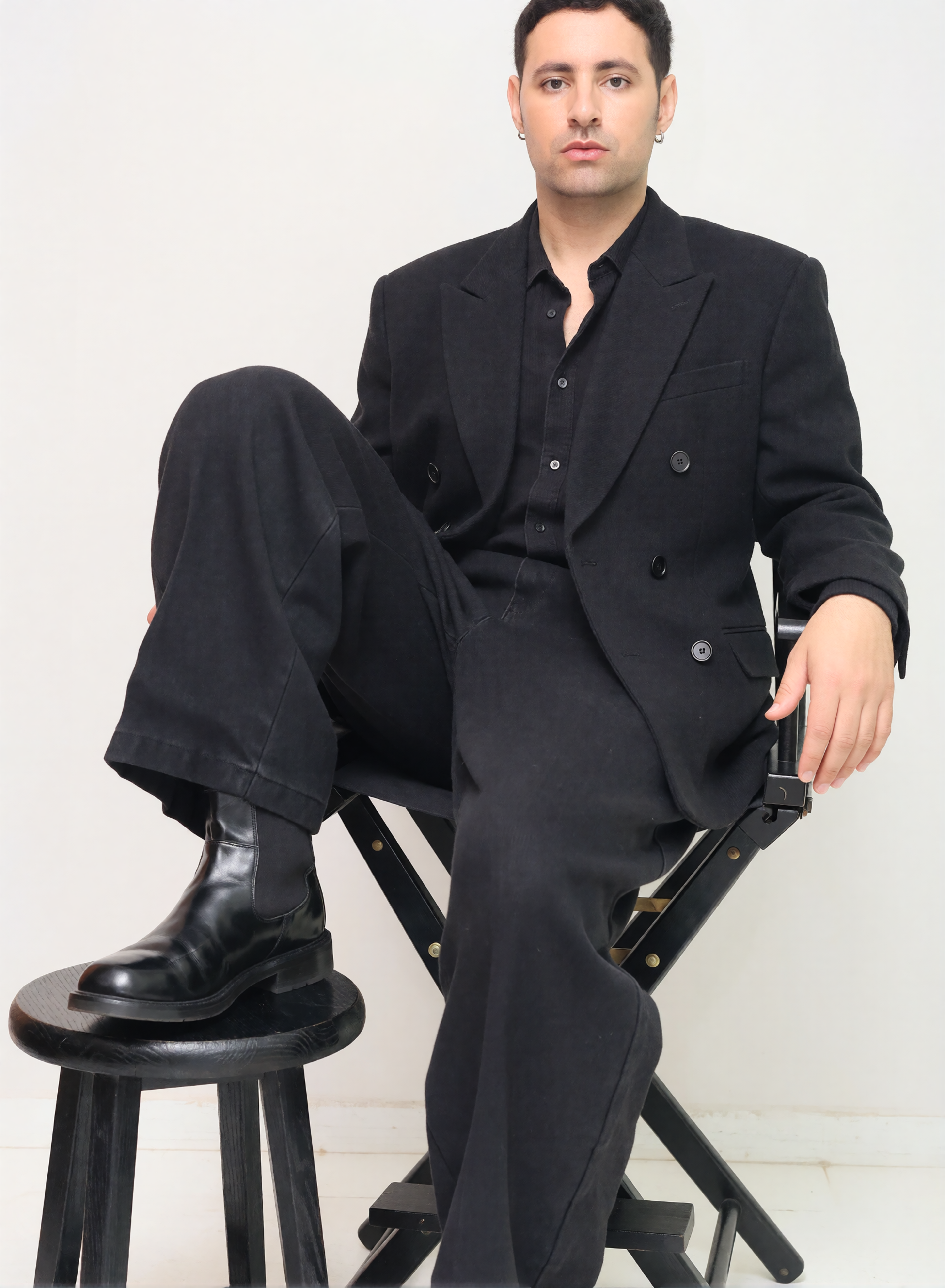 Digitaler Zwilling von Bruno Dias im schwarzen Zweireiher mit Hemd, weiter Hose und Lederstiefeln bei einem Studio-Fashion-Shooting.