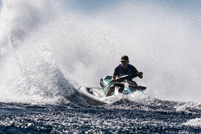 A rider carving a tight turn on a jet ski, throwing spray