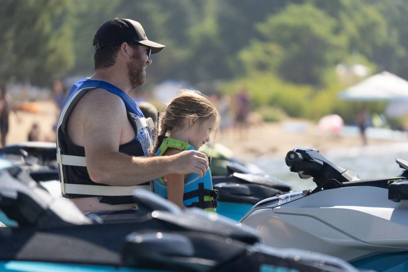A father and his daughter in life jackets on a jet ski