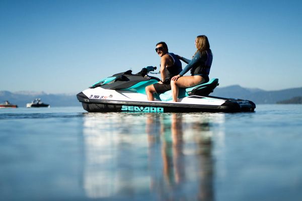 Two riders heading out on a jet ski over calm water