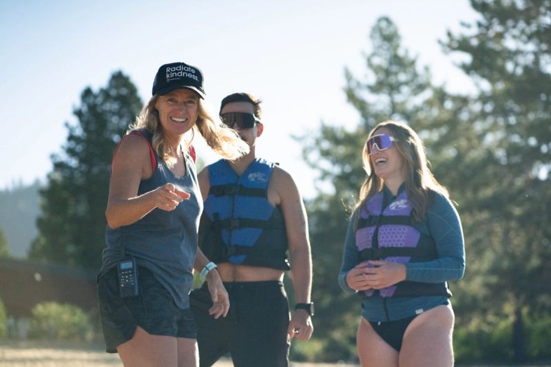 Three friends in life jackets laughing on the beach