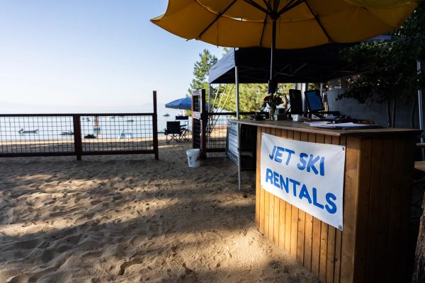 The jet ski rentals stand on the sand under a yellow umbrella