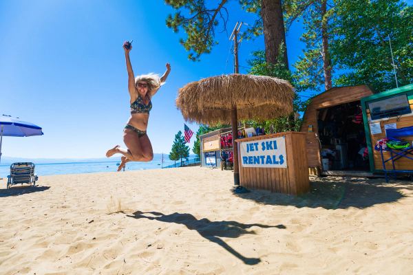 A rider jumping for joy on the beach next to the jet ski rentals stand