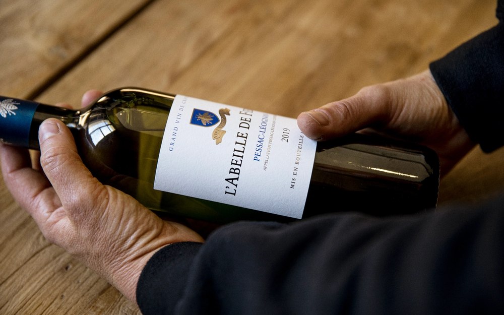 hands holding l'abeille de Fieuzal bottle