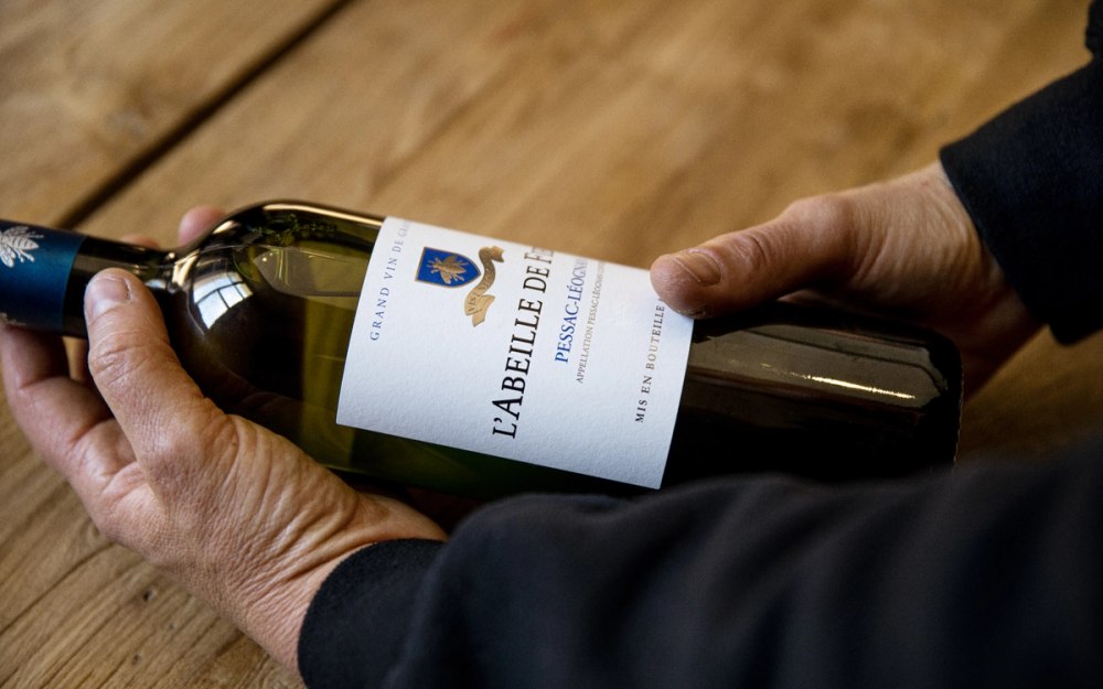 hands holding l'abeille de Fieuzal bottle