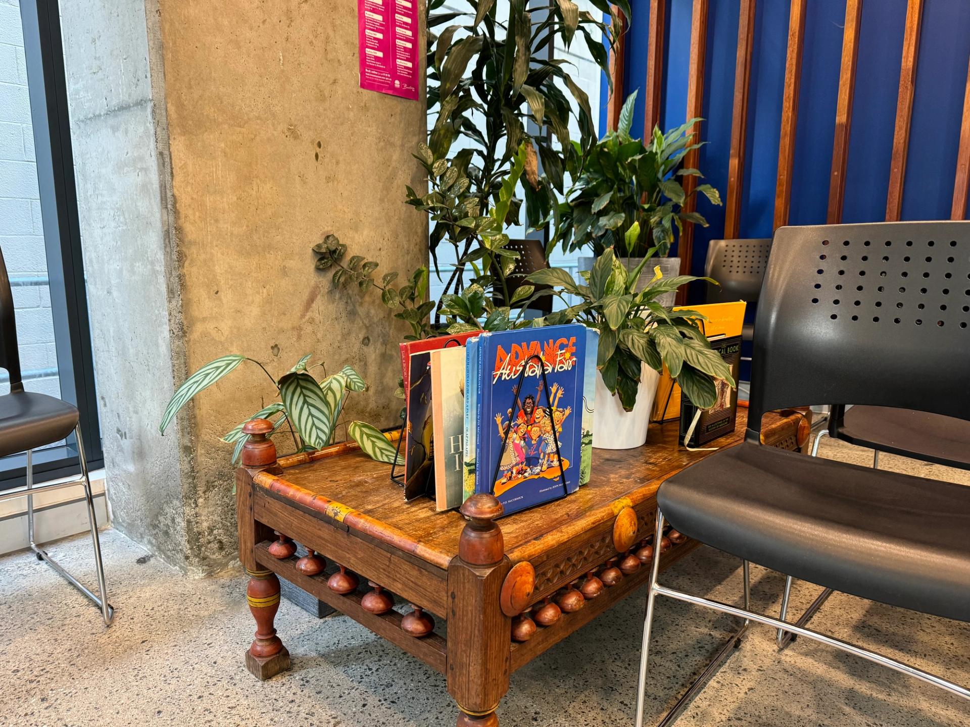 two books are sitting on a wooden table next to a chair .