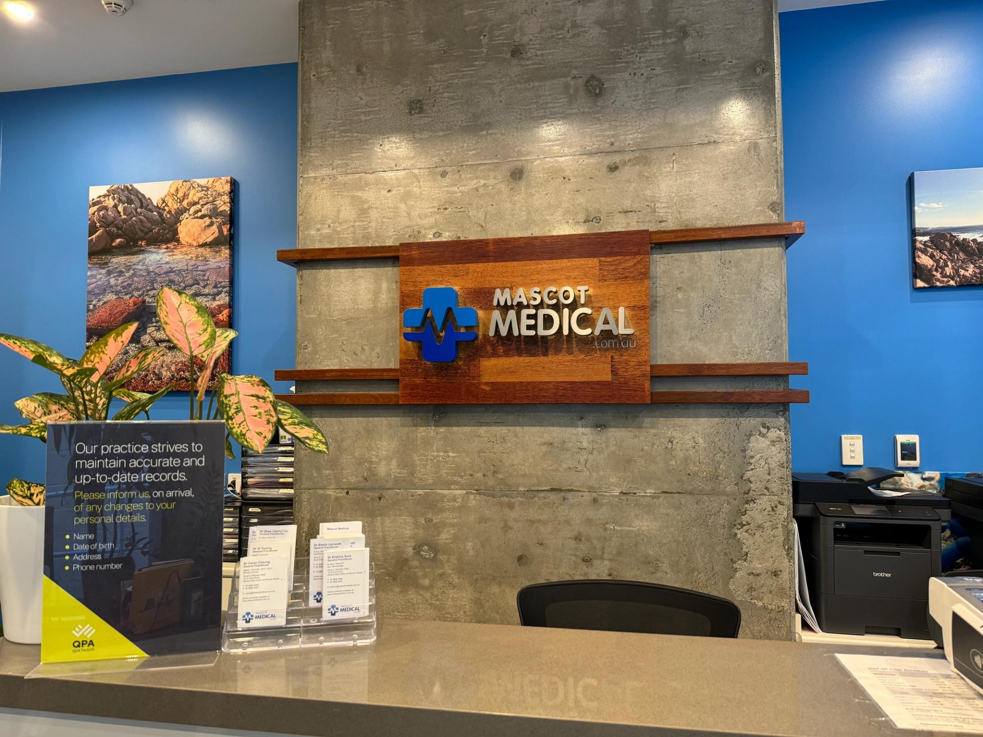 the front desk of a mascot medical office with a sign above it .