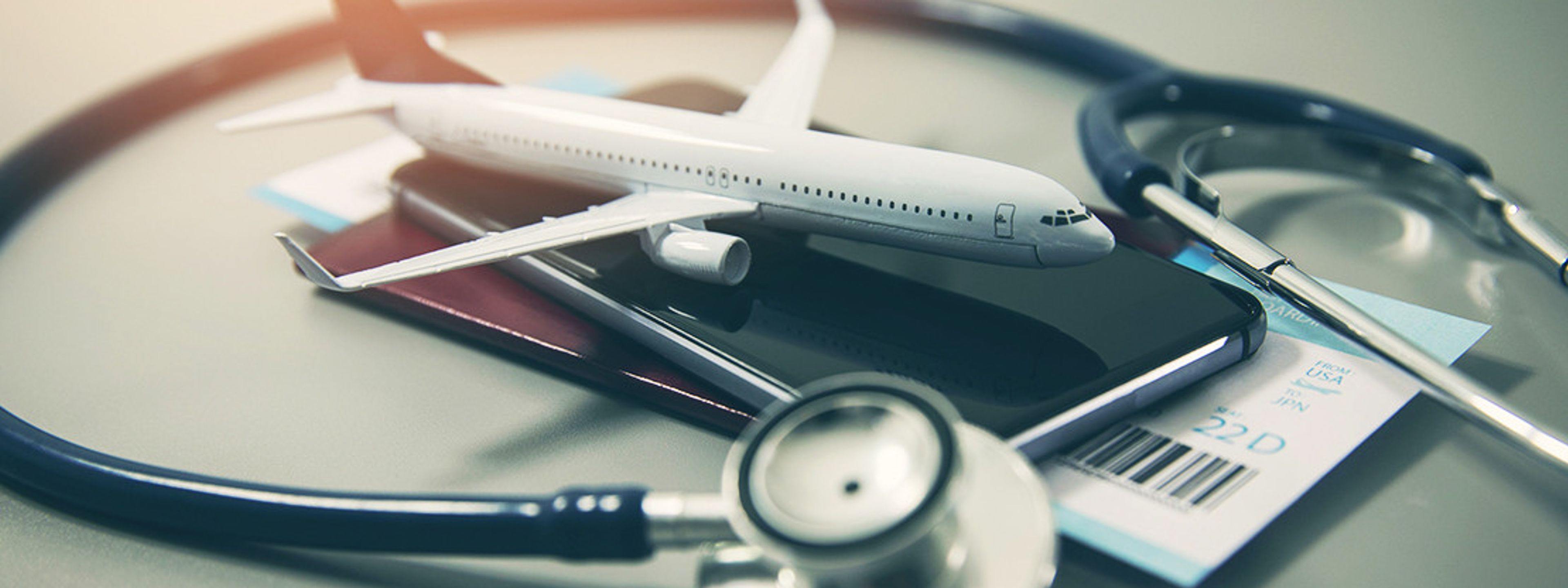 a stethoscope , passport , cell phone , and model airplane on a table .