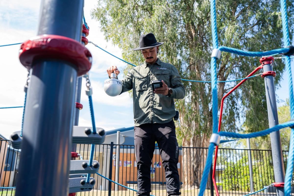 A Play Force inspector uses equipment to check if the soft fall on the ground is in line with Australian standards.