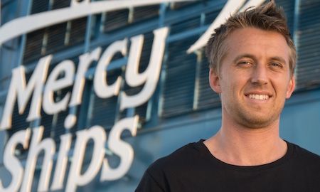 Crew photo of Nathan Foote in front of the Africa Mercy. 