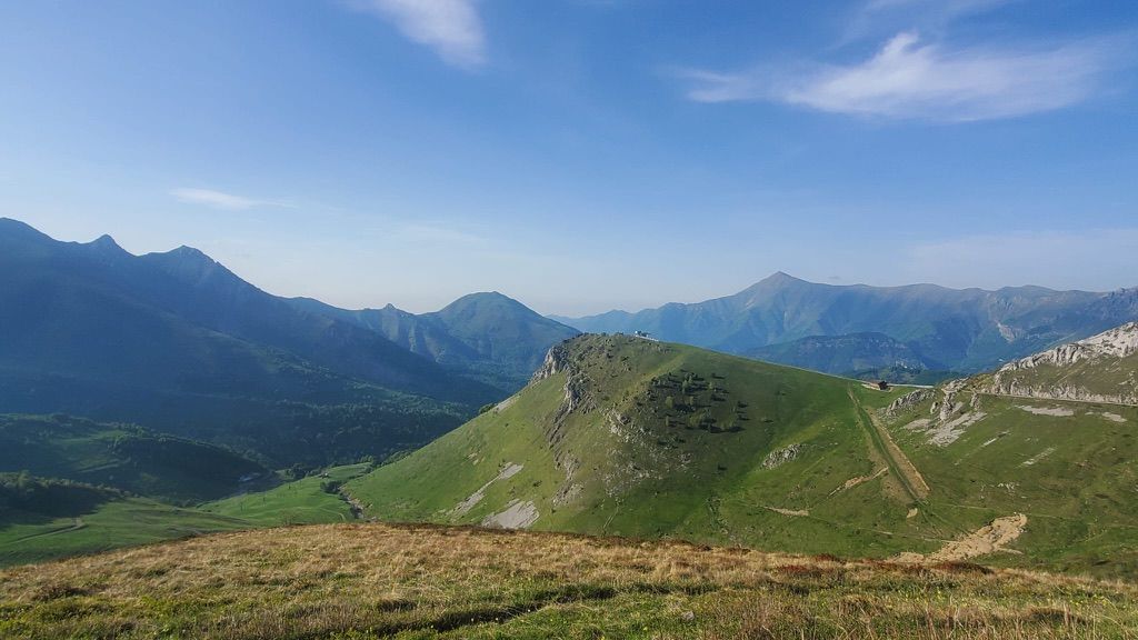 a view of a mountain range from the top of a grassy hill .