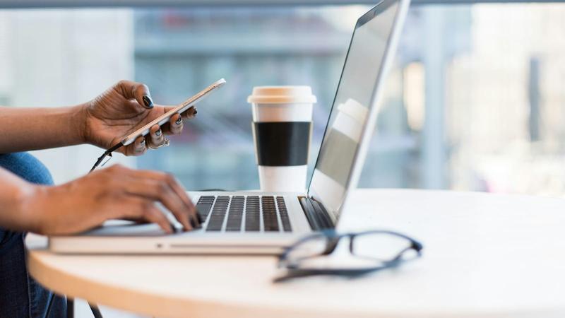 person using smartphone and MacBook