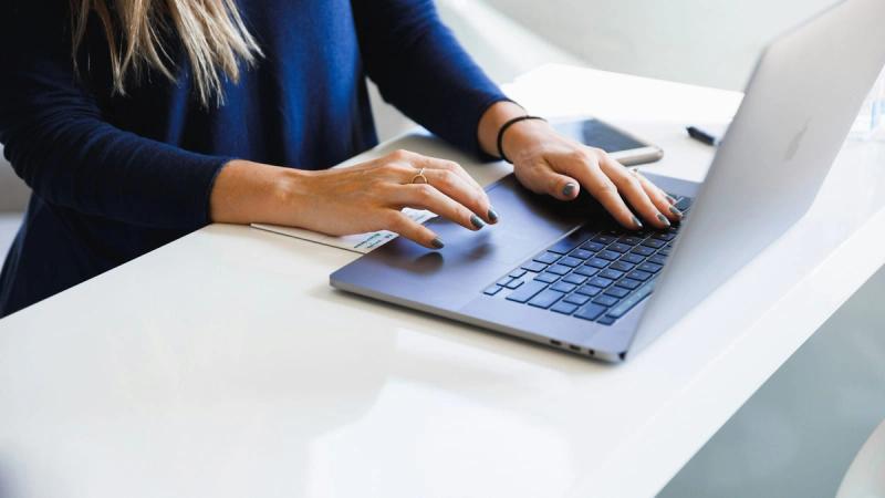 woman in blue long sleeve shirt using macbook pro