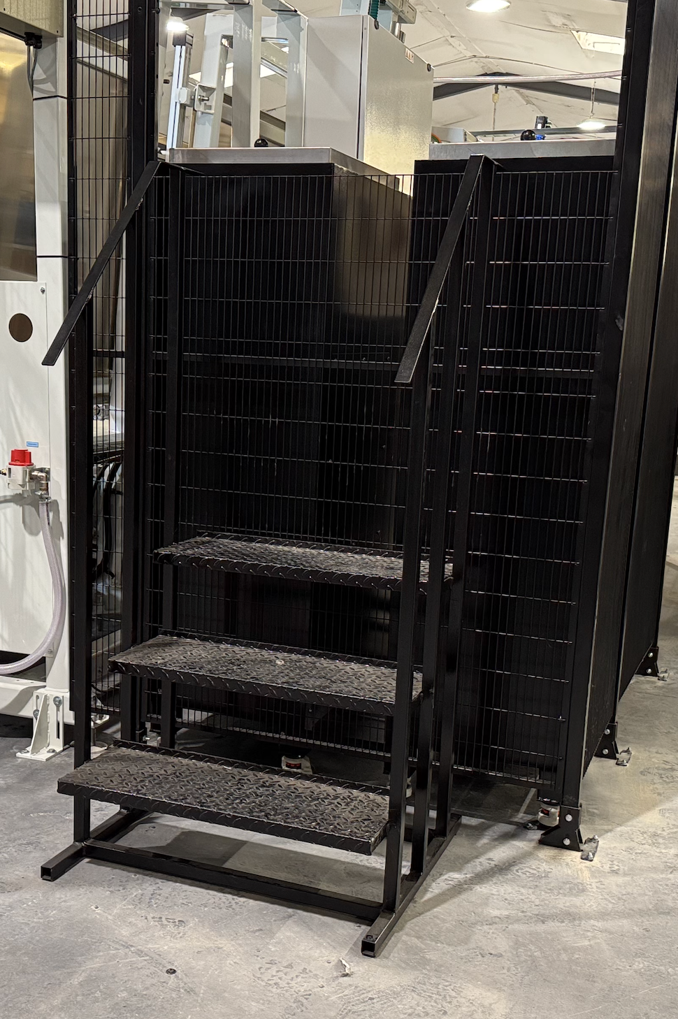 Safe and easy-access operator steps positioned outside the robot safety enclosure, providing secure access to the hot melt machine for loading, while keeping personnel separated from the automated sealing line.
