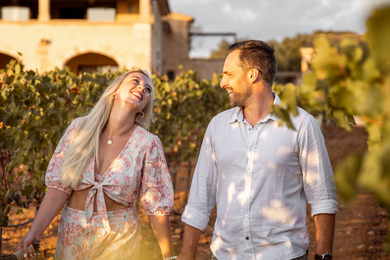 Par som nyter en romantisk stund i vinranker på Mallorca med varm kveldssol.