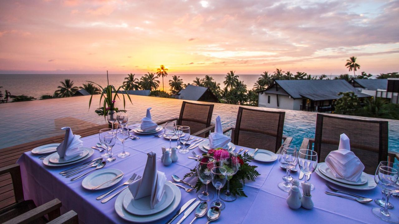 Bryllupsbord ved solnedgang på Koh Chang, med utsikt over havet og tropiske palmer.