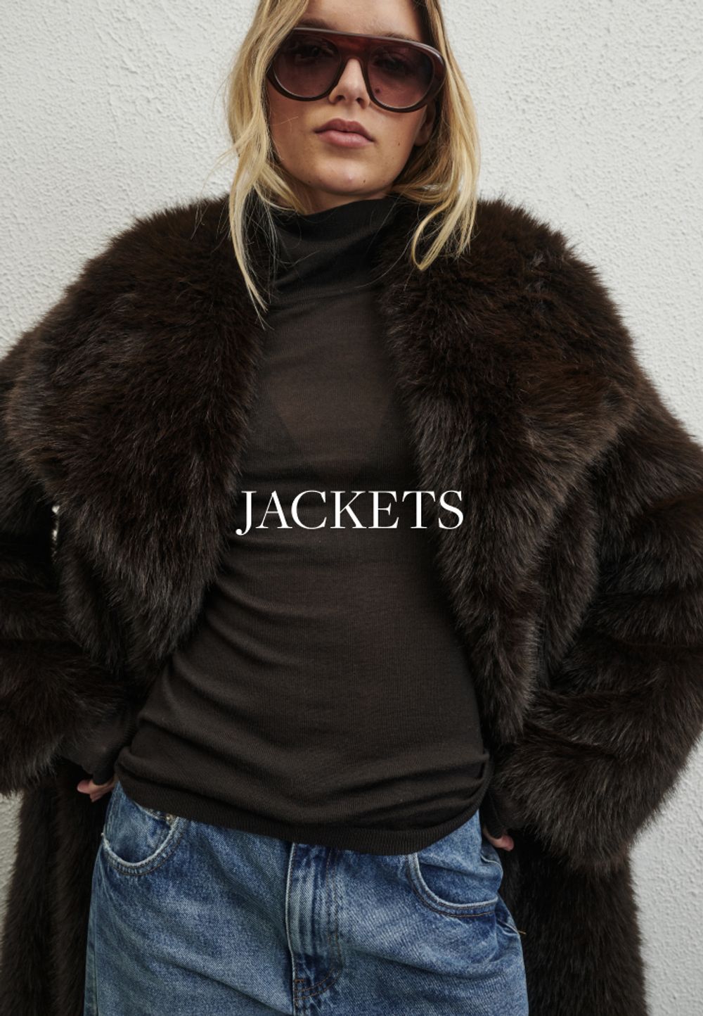 Model wearing a brown faux fur jacket. SHOP JACKETS.