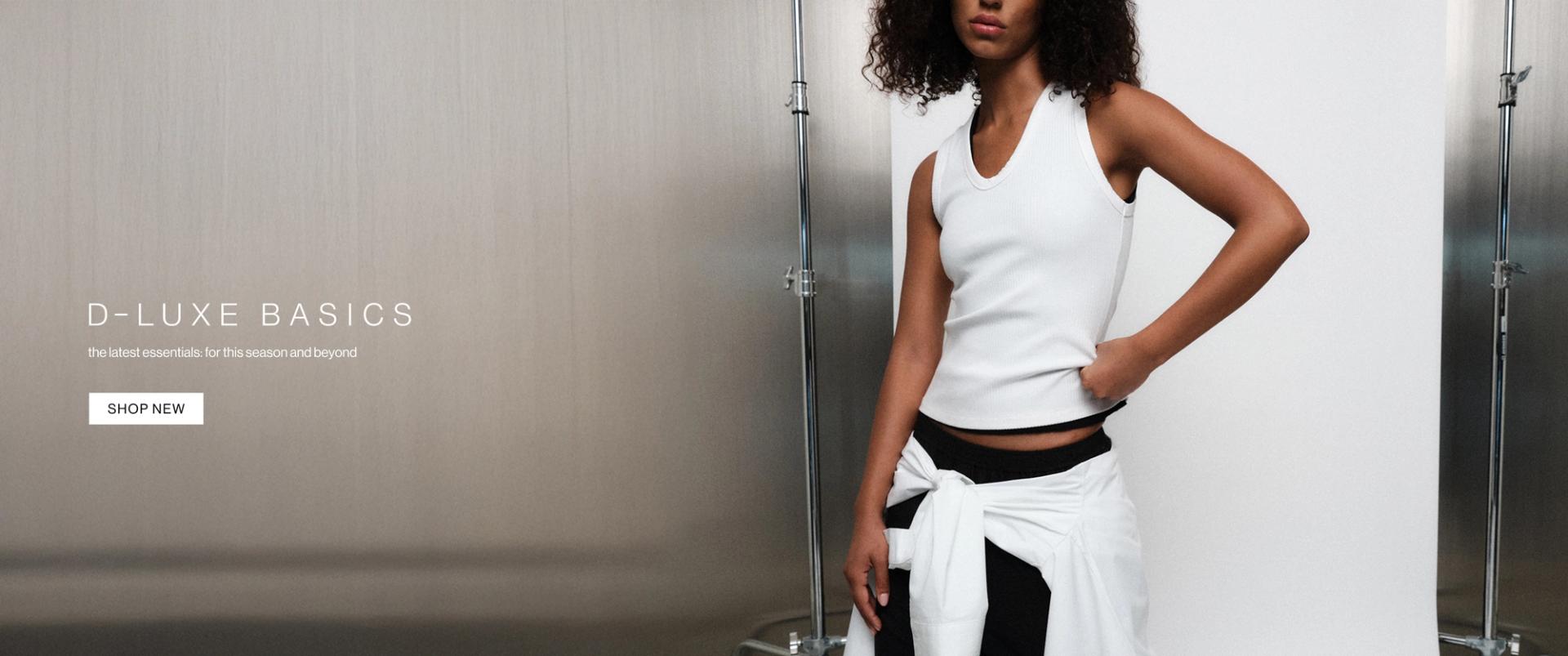 Model in a white tank and black pant with white shirt wrapped around waist against a modern metallic wall with “D-Luxe Basics” headline.