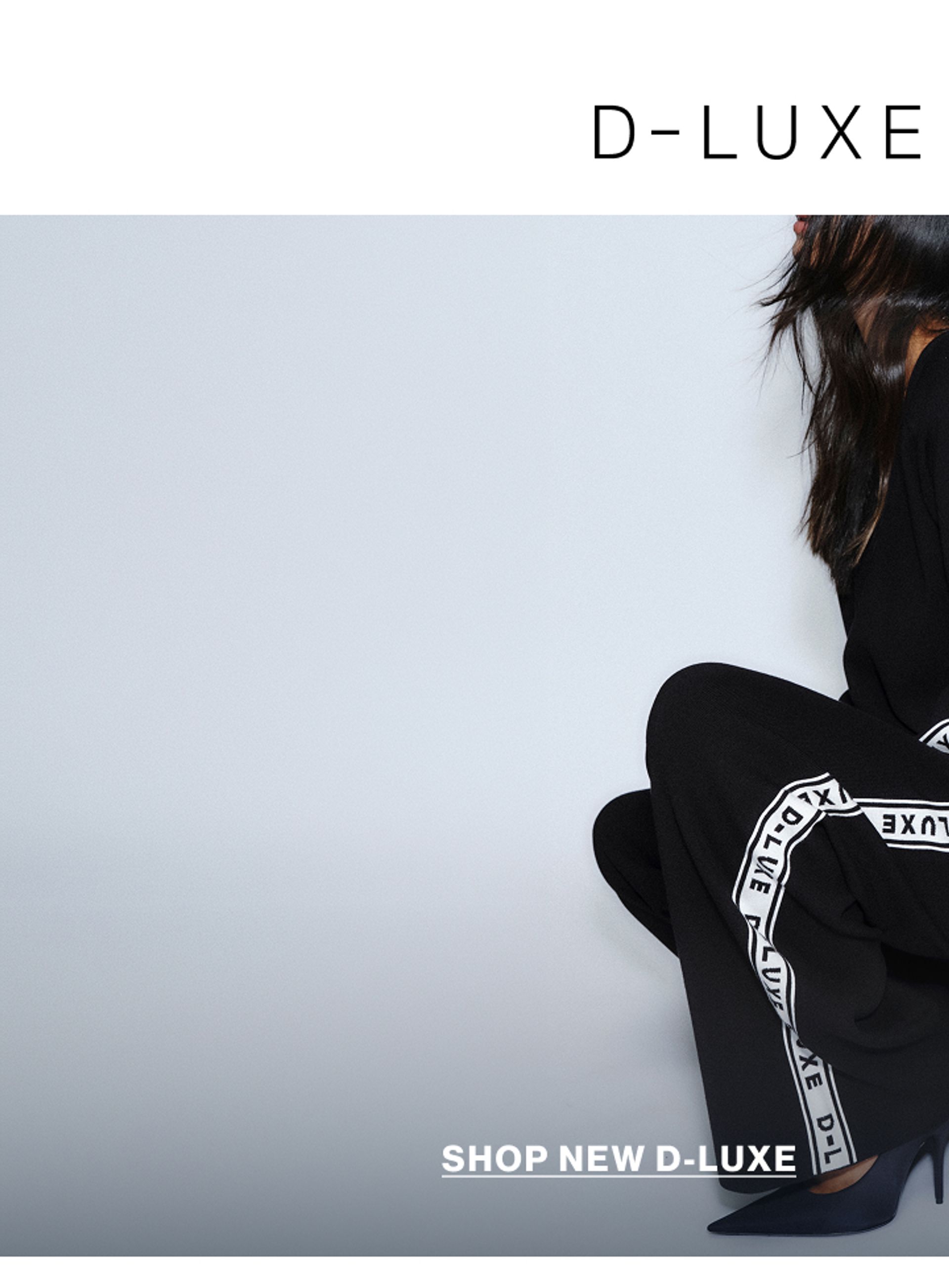 Model wearing a black knit with white logo branding in a studio. Text reads D-LUXE BASICS