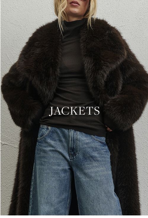 Model wearing a brown faux fur jacket. SHOP JACKETS.