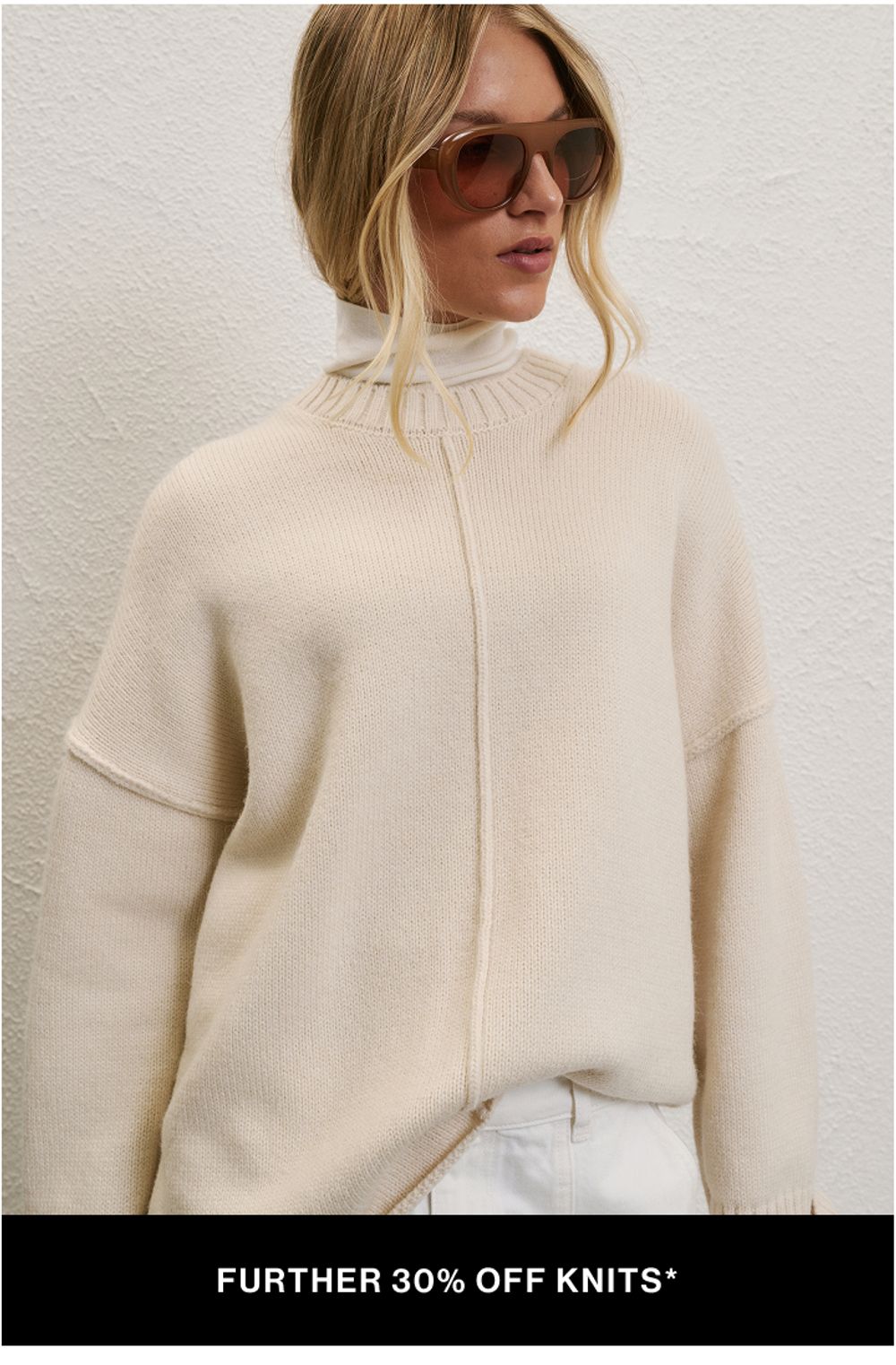 A model wearing a cream knit against a neutral background. SHOP FURTHER 30% OFF SALE KNITS.