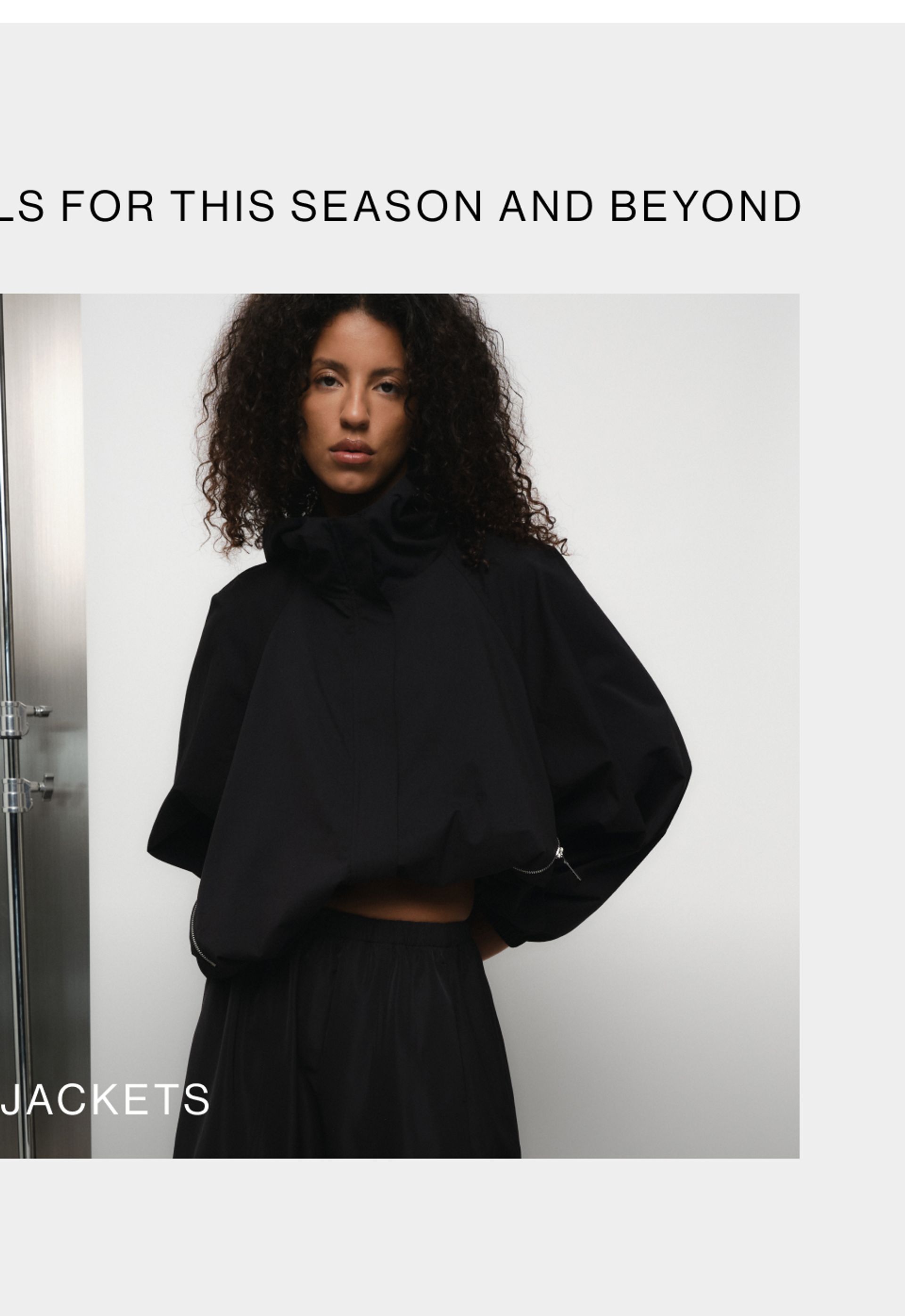 Model wearing a black high neck jacket against a neutral background. SHOP D-LUXE JACKETS.