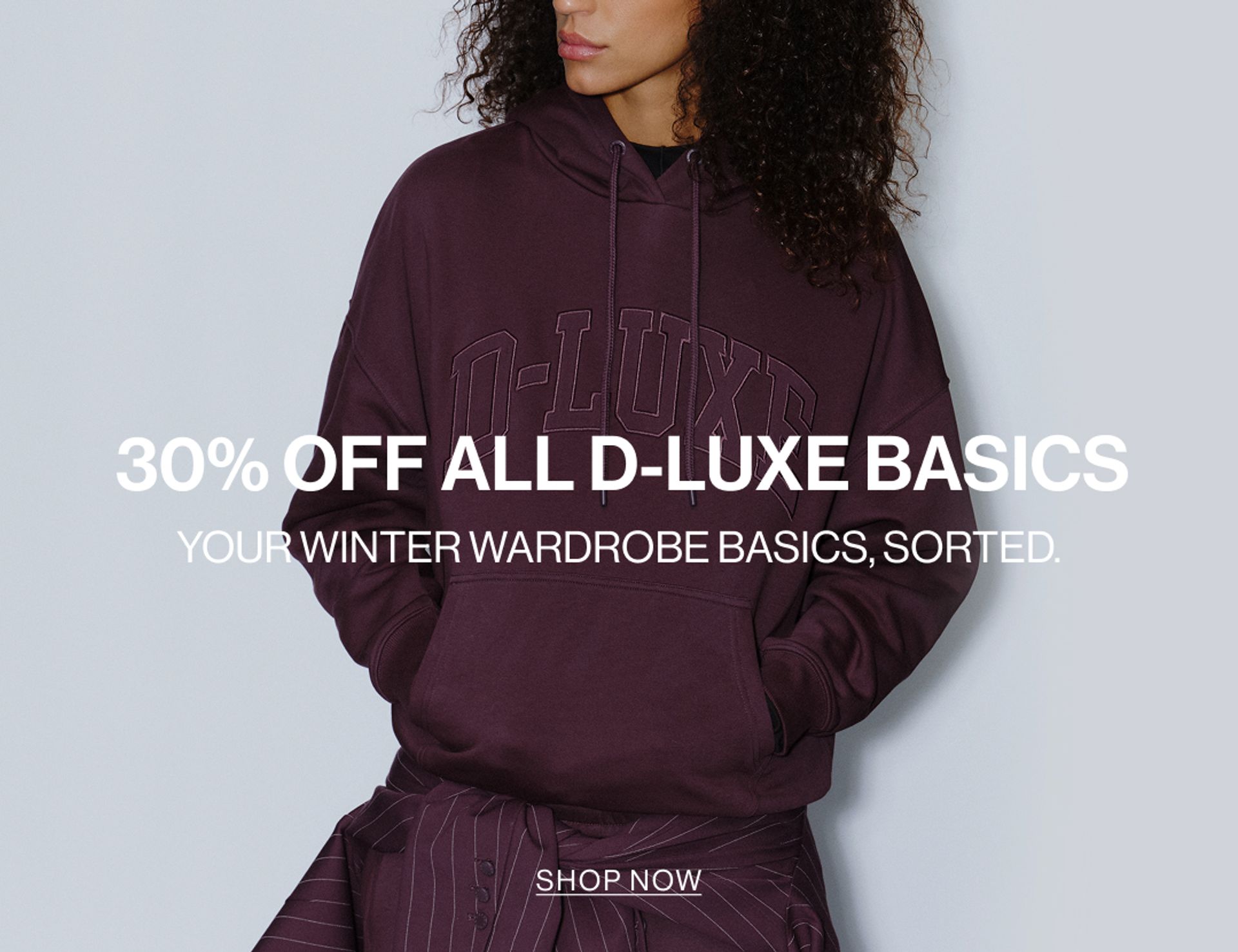 Model wearing a sweat set in midnight cherry in a studio. SHOP NEW D-LUXE.