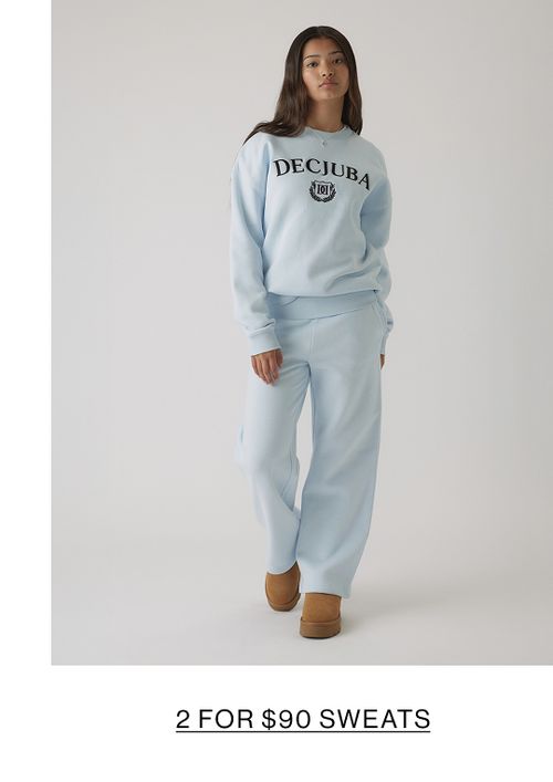 Young girl in a light blue matching tracksuit set with a front graphic, standing in a relaxed pose.