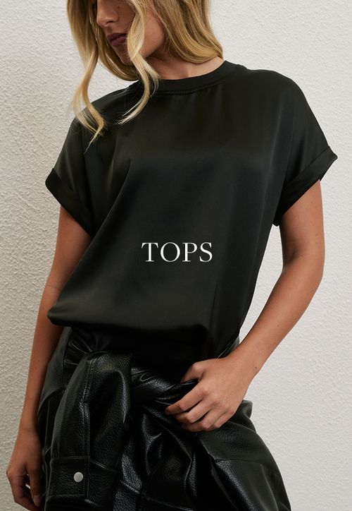 Model wearing a black satin tee. SHOP TOPS.