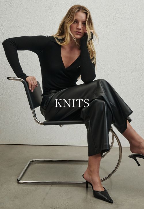 Model wearing a black knit. SHOP KNITS.