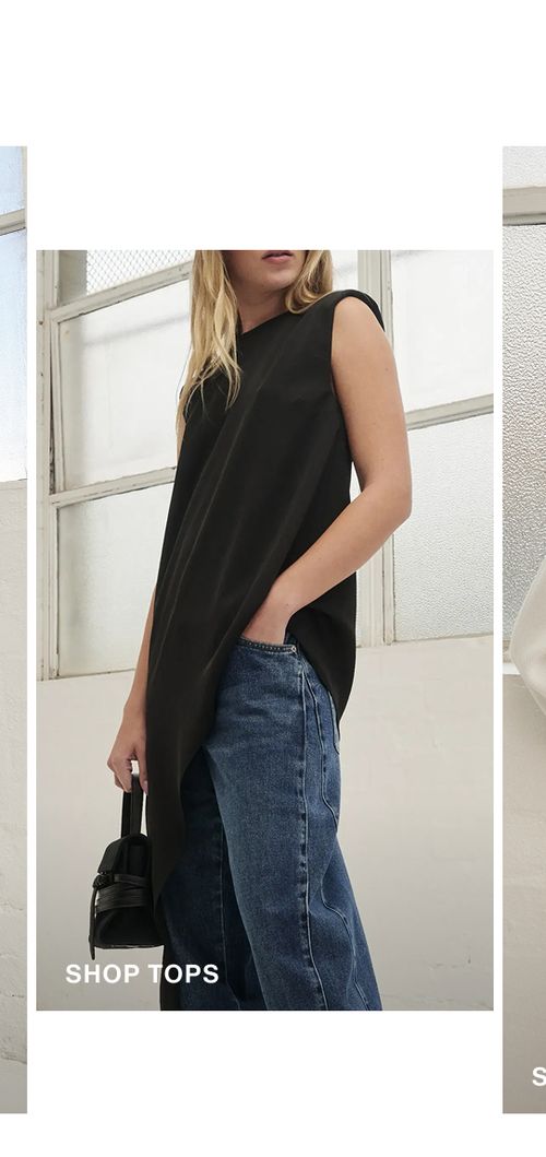 Model posing wearing a black side drape top. SHOP TOPS.