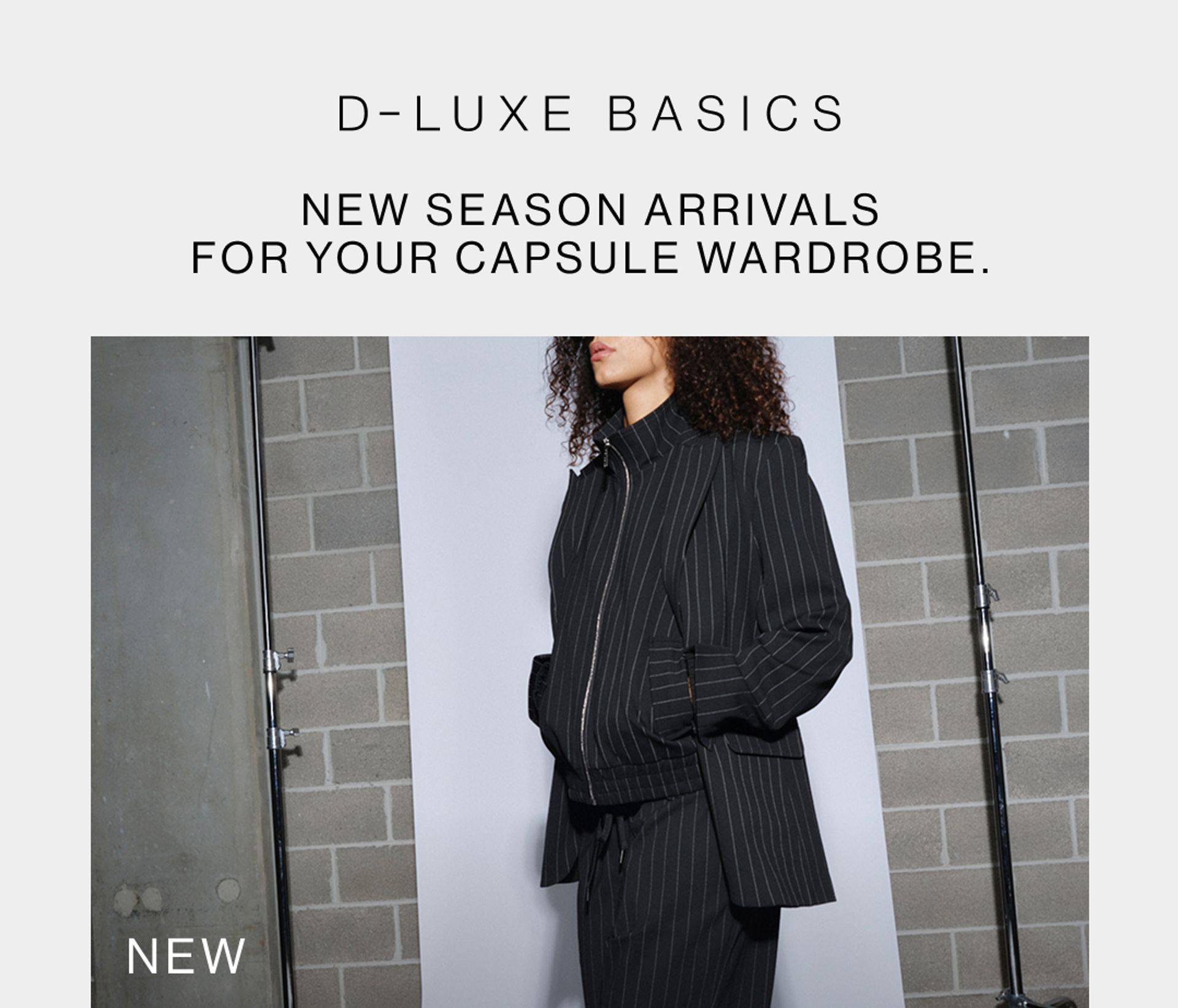 Model wearing black pinstripe suit in a studio. SHOP NEW D-LUXE.