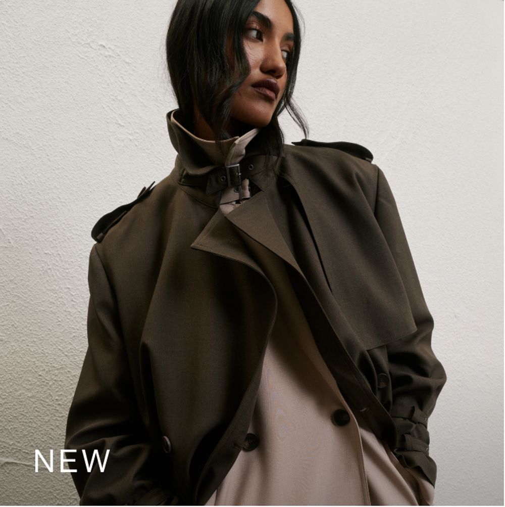 Model wearing a khaki trench. SHOP NEW.