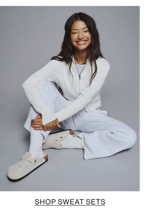 Young girl wearing a grey sweatshirt and ripped jeans with a denim jacket tied at the waist.