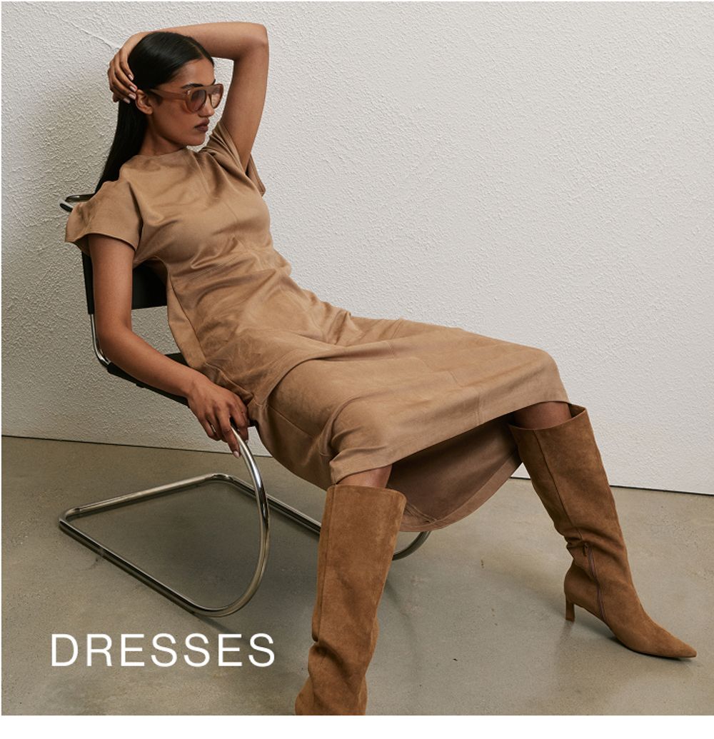 Model wearing a black high neck midi dress. SHOP DRESSES.