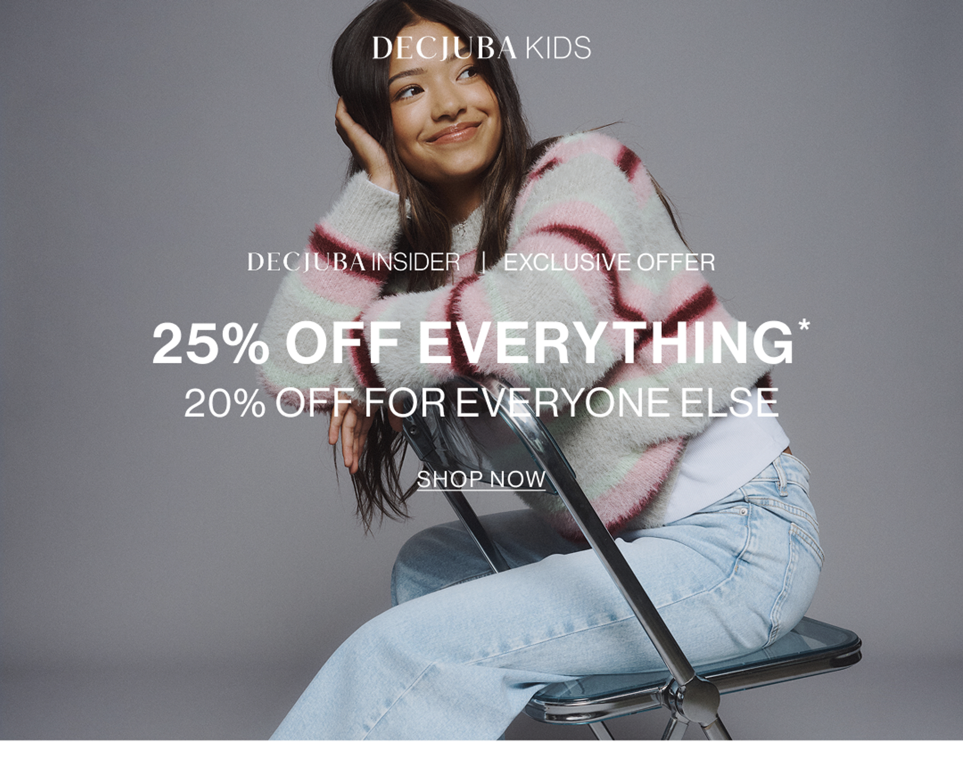 Young model wearing a striped knit with light blue jeans sitting on a chair. SHOP 25% OFF KIDS.