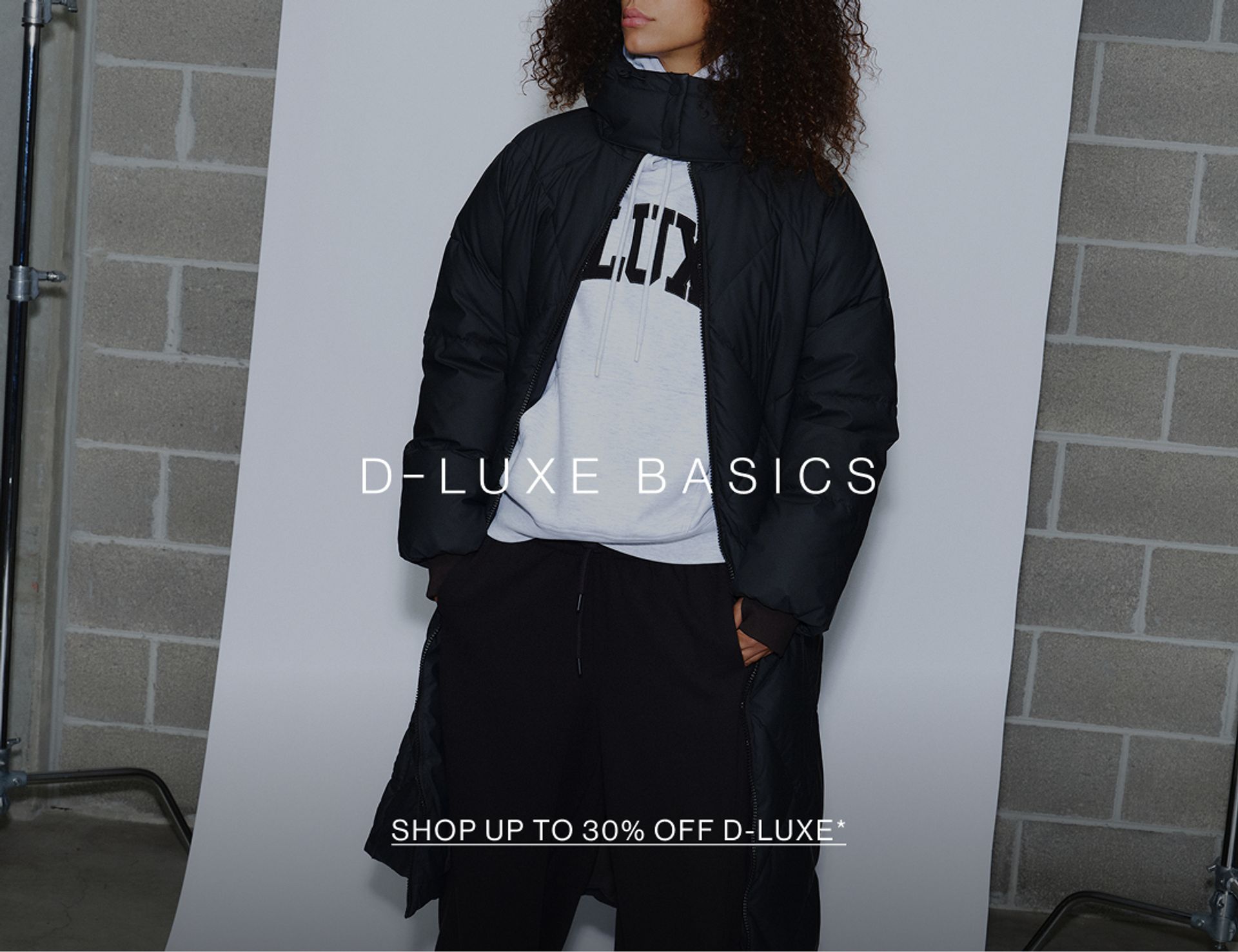 Model wearing a puffer jacket in midnight cherry in a studio. SHOP NEW D-LUXE.