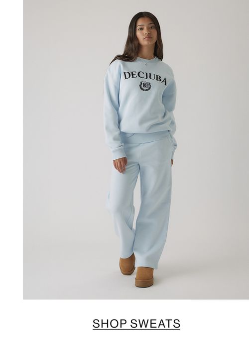 Young girl in a light blue matching tracksuit set with a front graphic, standing in a relaxed pose.