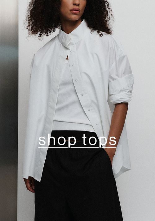 Model in a white shirt and black pants with hand in front pocket