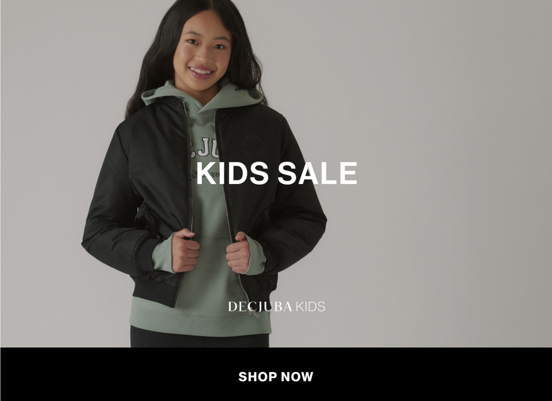 Model wearing a green hoodie and black bomber in a studio. Text reads KIDS SALE.
