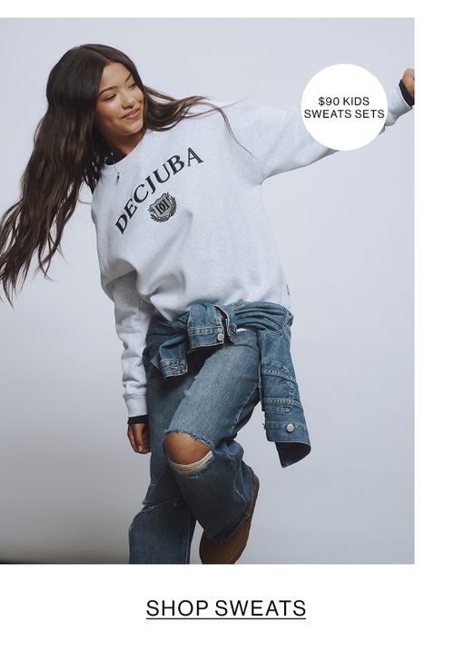 Young girl wearing a grey sweatshirt and ripped jeans with a denim jacket tied at the waist.