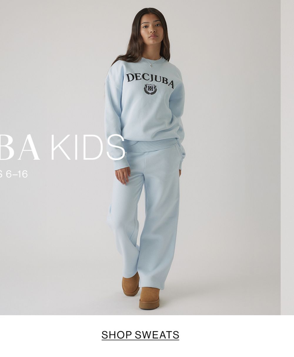 Young girl in a light blue matching tracksuit set with a front graphic, standing in a relaxed pose.