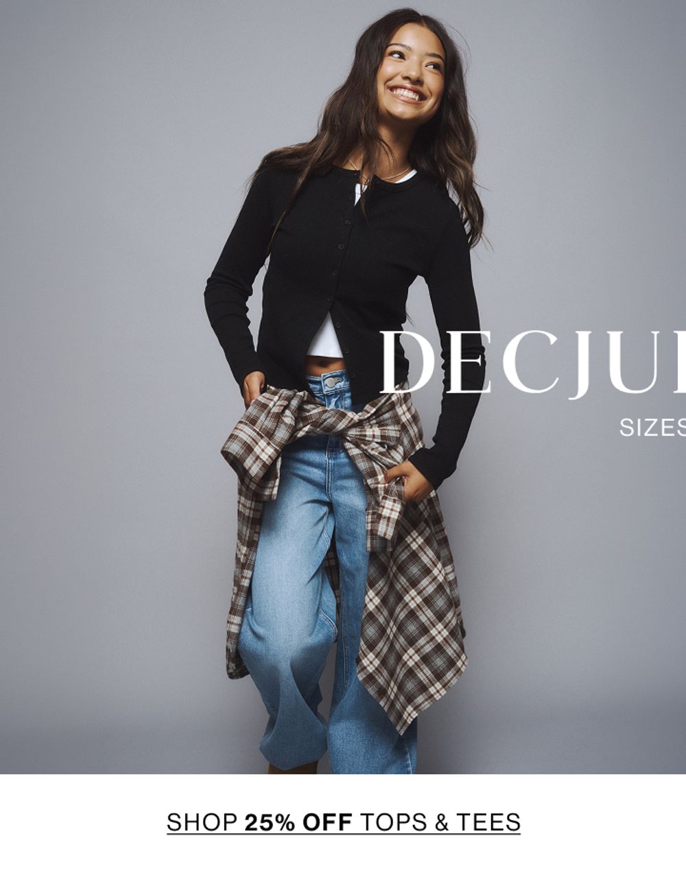 Young girl sitting cross-legged wearing a denim jacket, jeans, and sneakers