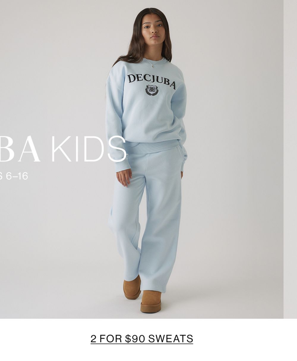 Young girl in a light blue matching tracksuit set with a front graphic, standing in a relaxed pose.